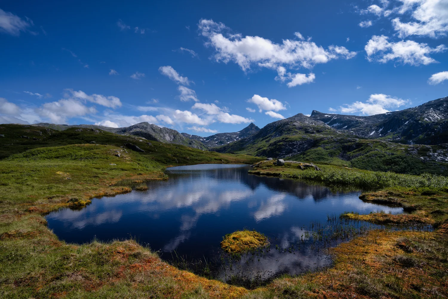 Kleiner See in den Bergenn unter hellblauem Himmel