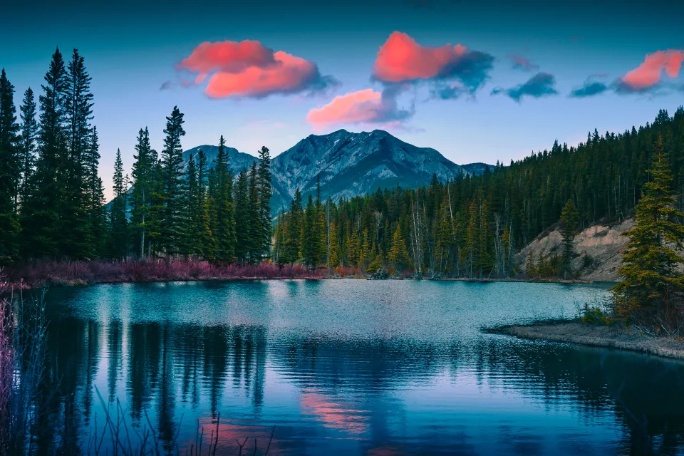 Rote Wolken in Himmel über Berge am See