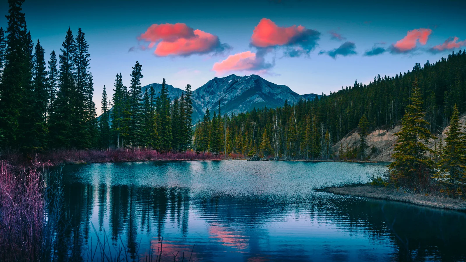 Rote Wolken in Himmel über Berge am See