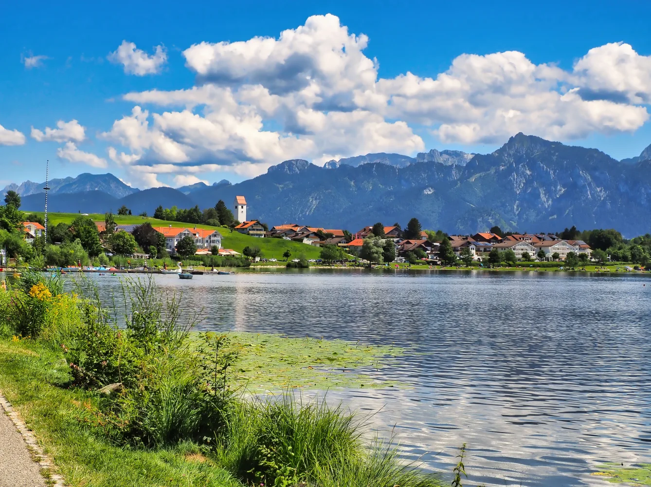 Schöner Blick auf See und Berge unter hellblauem Himmel mit weißen Wolken