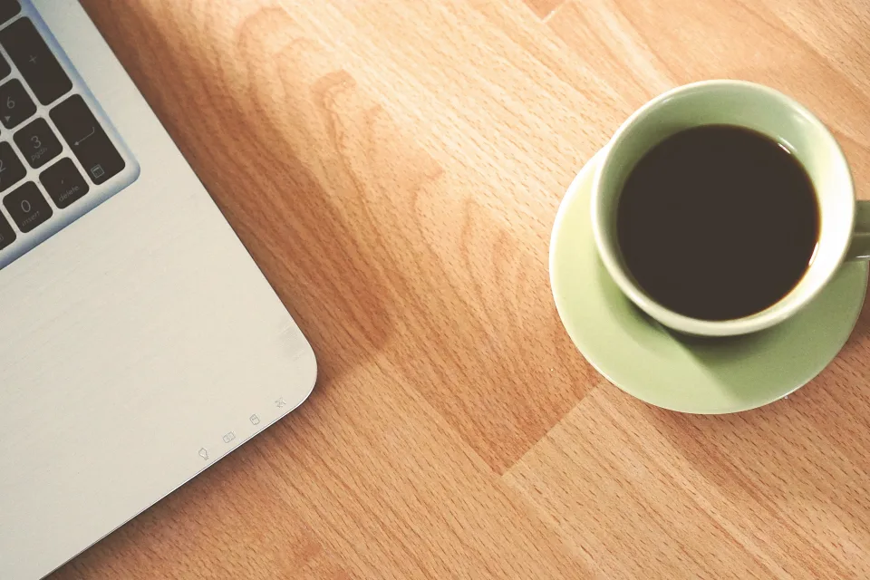 Weiße Keramiktasse neben MacBook