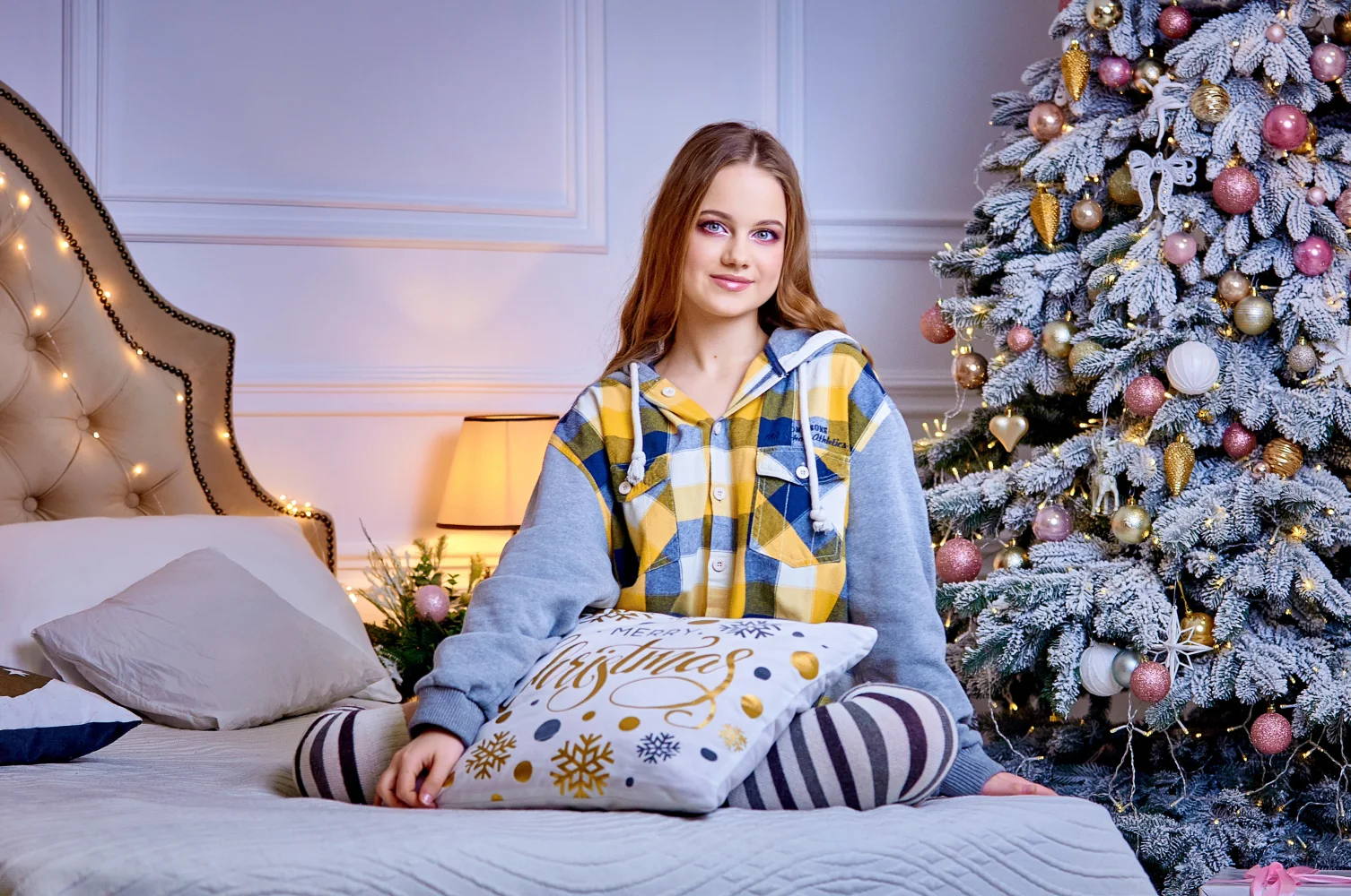 Hübsche Frau auf Bett am Weihnachtsbaum