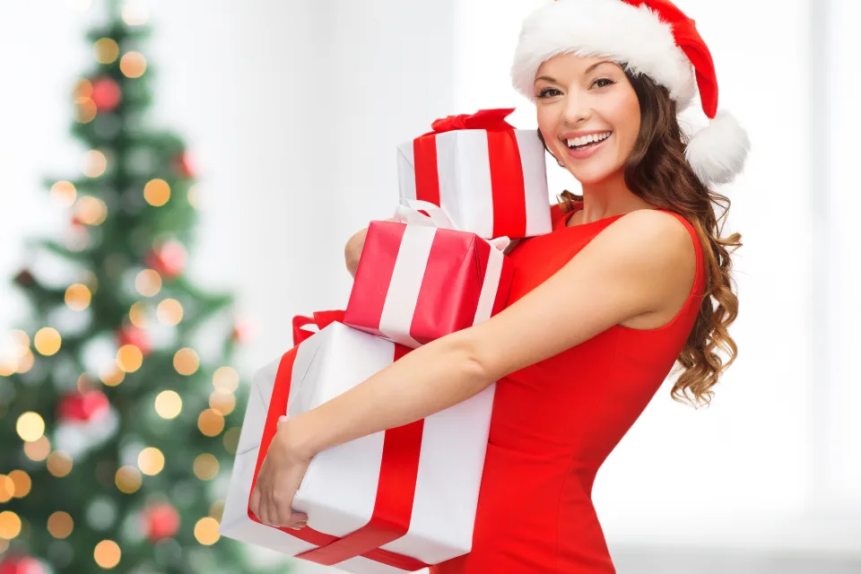 Lächelnde Frau in rotem Kleid mit Geschenken zu Neujahr