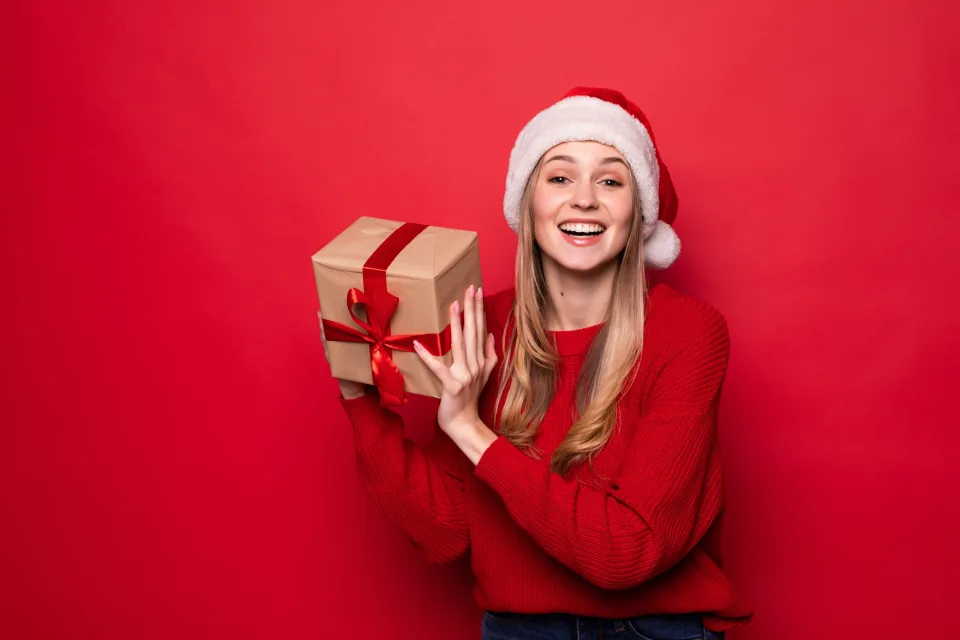 Lächelnde Frau mit einem Geschenk im festlichen Kostüm