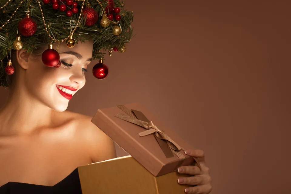Schöne Frau mit weihnachtlichen Kranz auf Kopf mit einem Geschenk