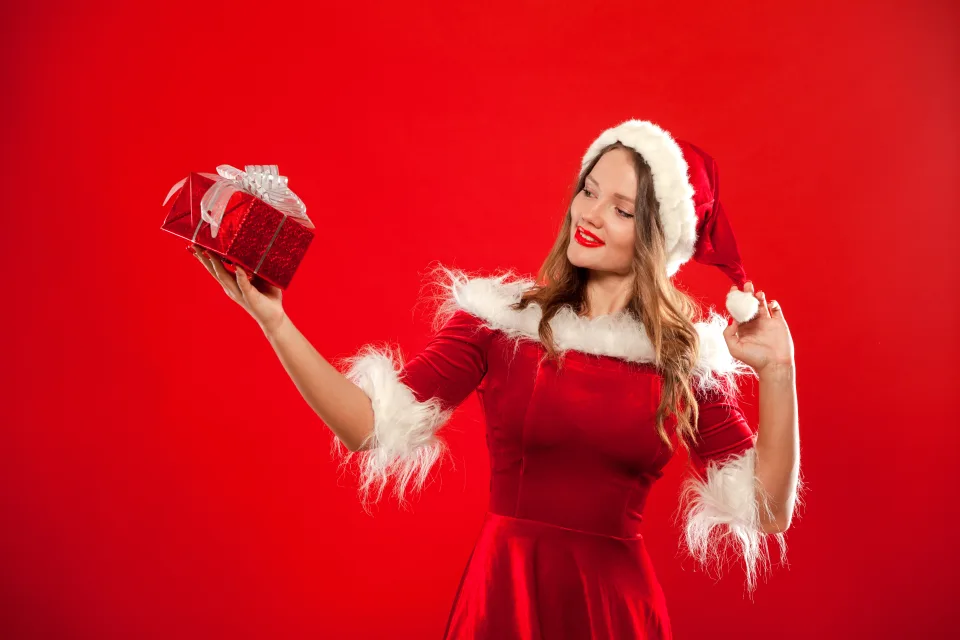Schöne Schneemädchen mit einem Geschenk in Hand vor rotem Hintergrund