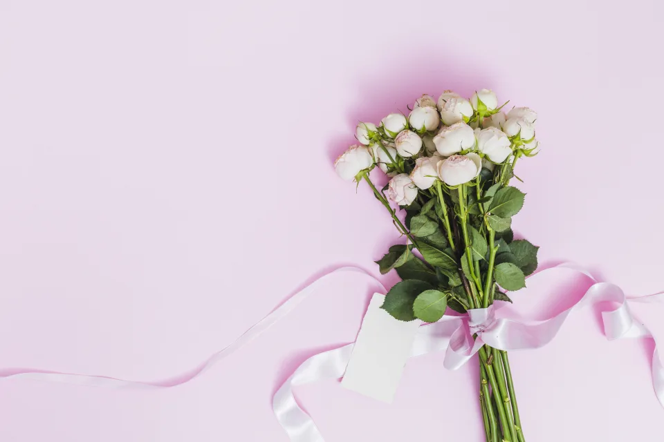 Blumenstrauß Rose mit Schleife vor rosa Hintergrund