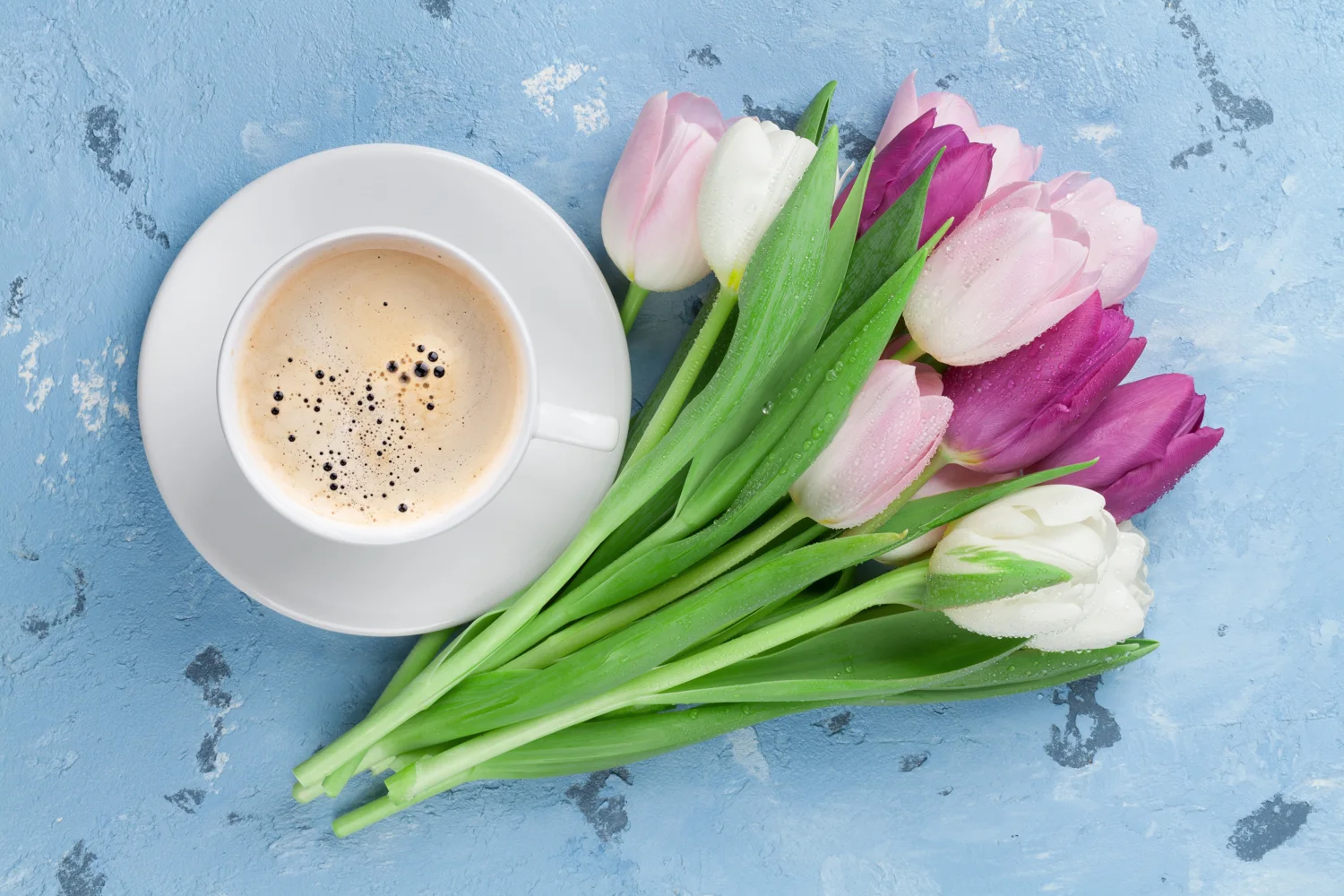 Blumenstrauß bunten Tulpen mit Tasse Kaffee auf hellblauem Tisch