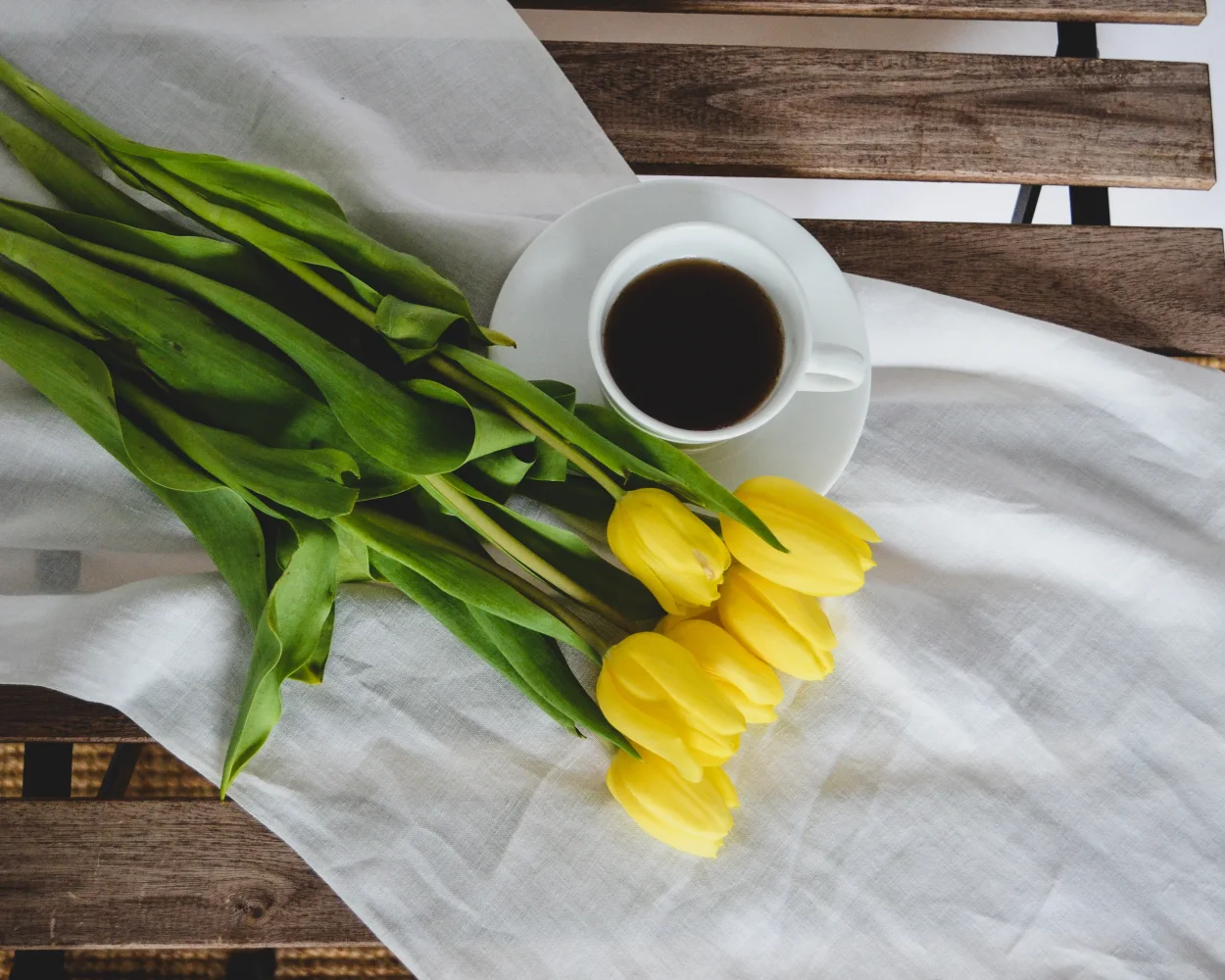 Blumenstrauß gelben Tulpen mit Tasse Kaffee auf Bank