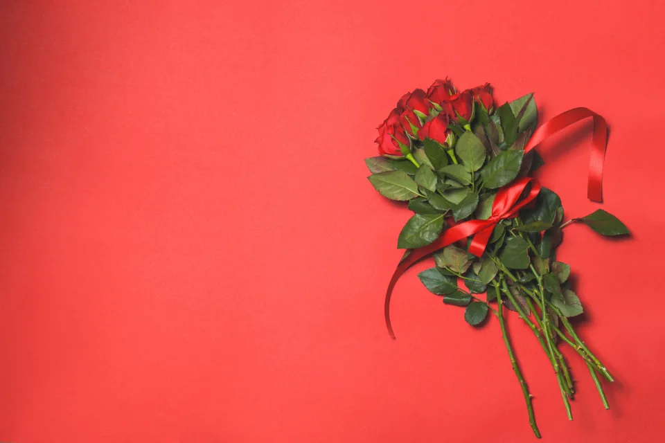 Blumenstrauß roten Rose mit Schleife vor rotem Hintergrund, Vorlage