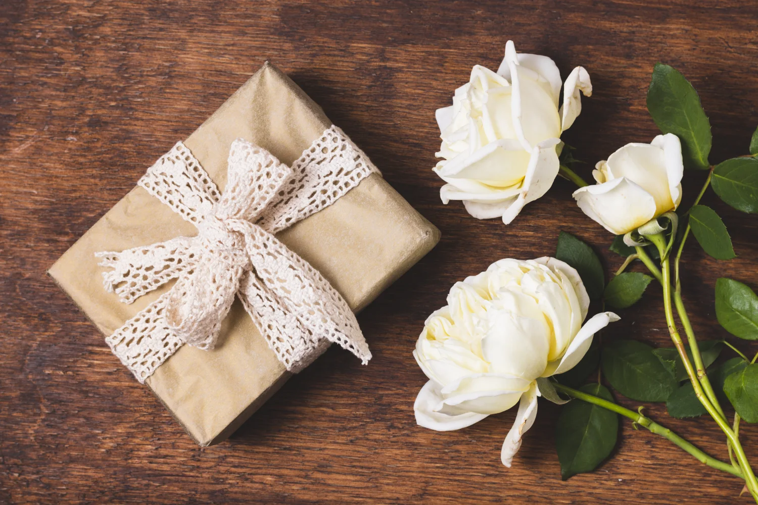 Geschenk auf hölzernem Tisch mit weißen Rose