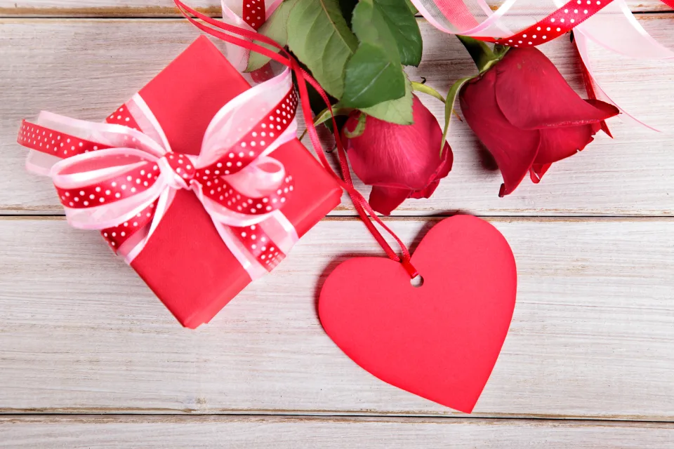 Geschenk und rotes Herz mit Rose für