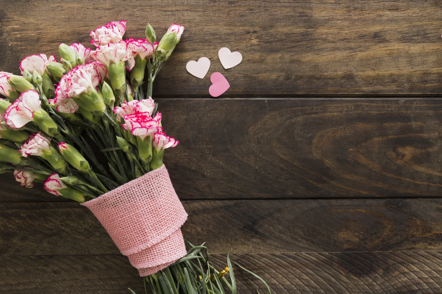 Rosa mit Herzen auf braunem hölzernem Hintergrund