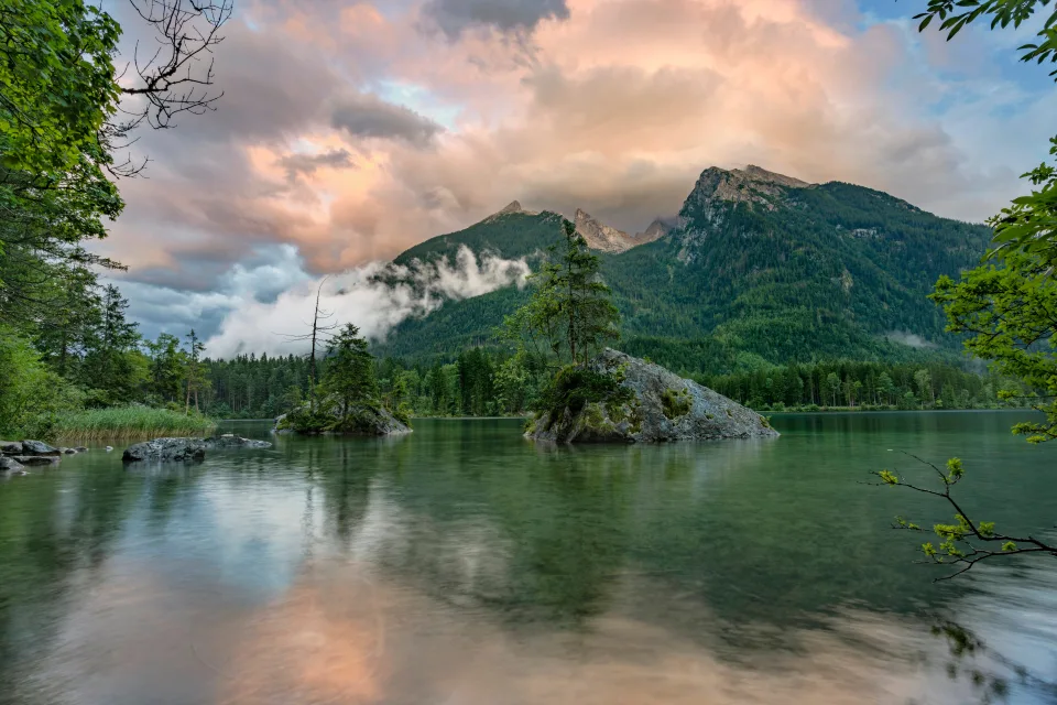 Bedeckte grüne Berge in den Wolken am See