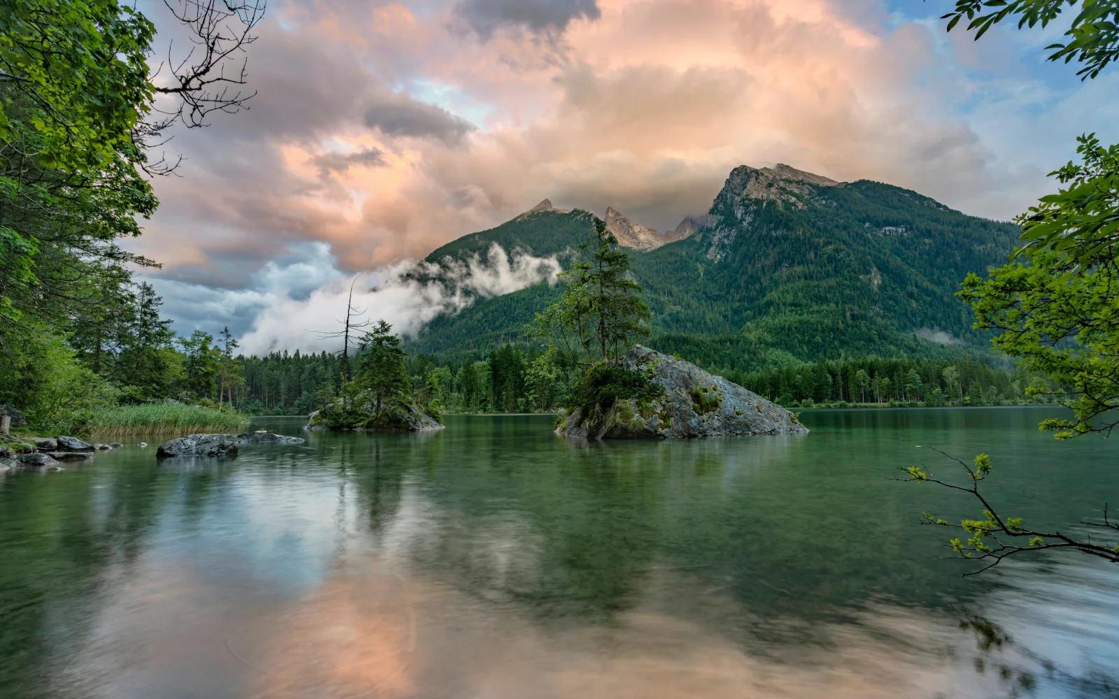 Bedeckte grüne Berge in den Wolken am See