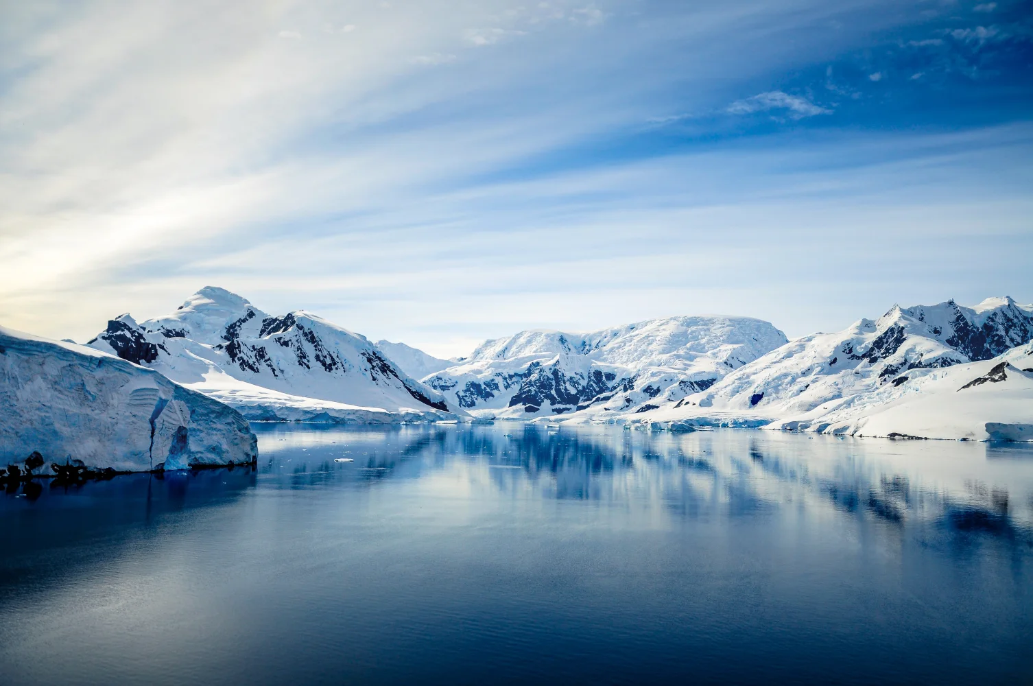 Bedeckte kaltem weißem Schnee Berge am Meer