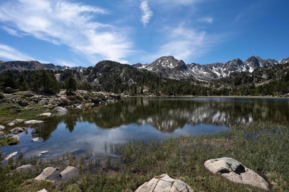 Berge spiegeln sich im See mit großen Felsen