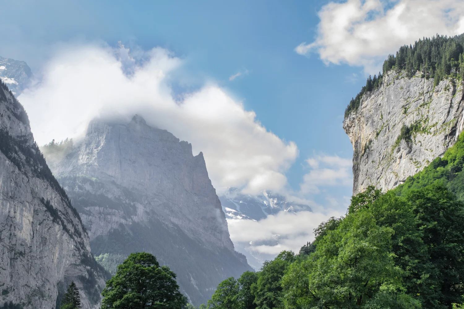 Hohe bedeckte grüne Berge in weißen Wolken