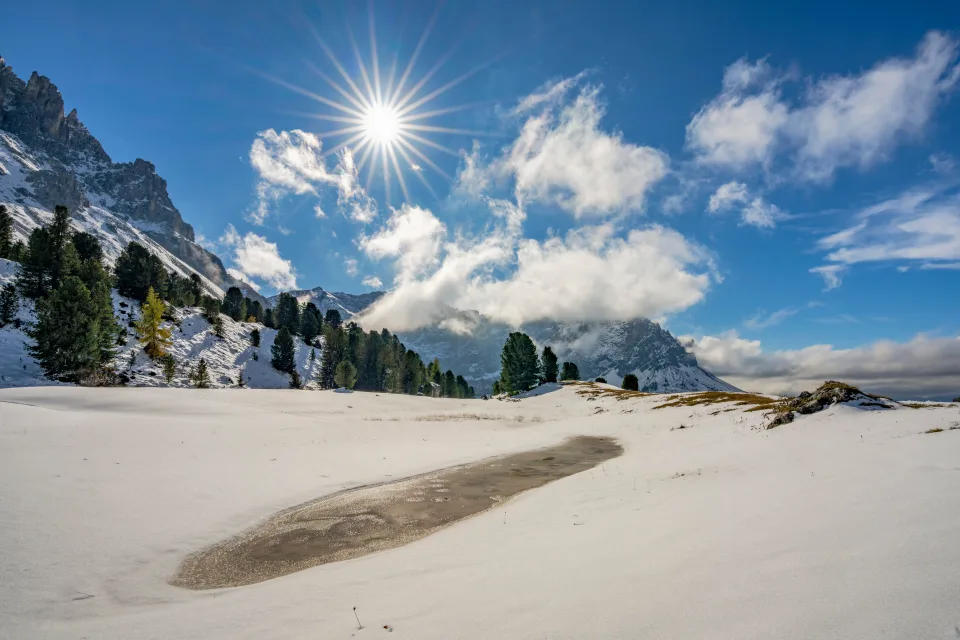 Leuchtende Sonne über Berge bei See