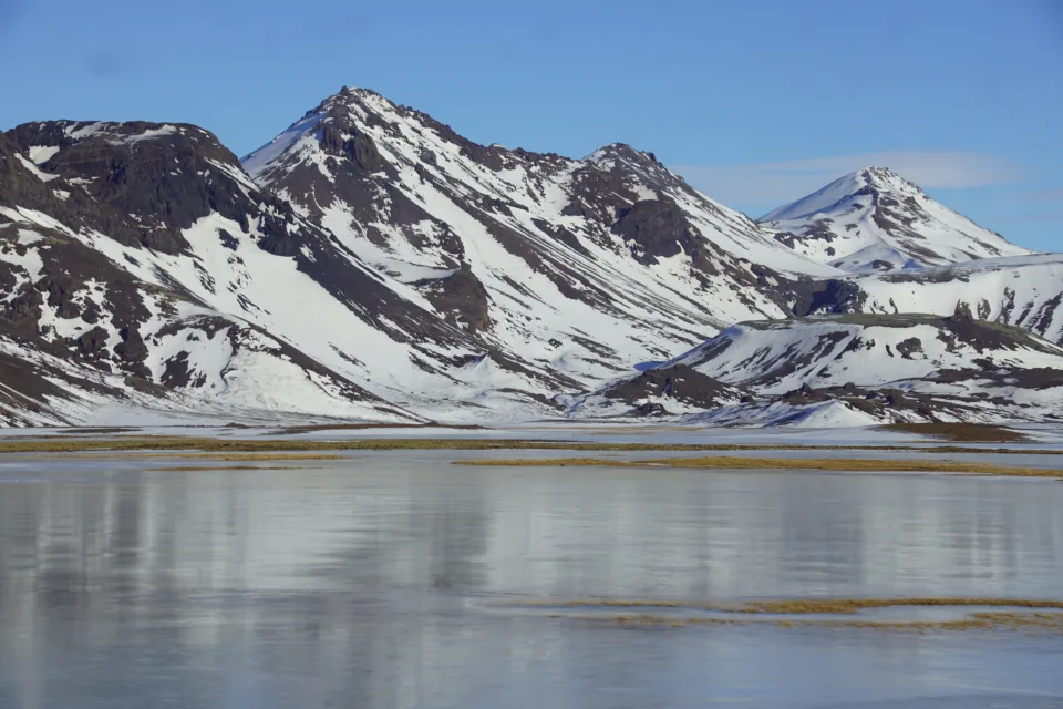 Schneebedeckte Berge unter hellblauem Himmel am Wasser