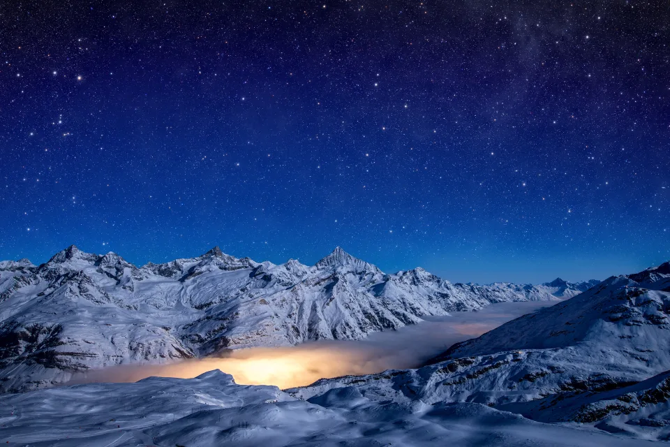 Schönes nächtliches Himmel über bedeckten Schnee Berge