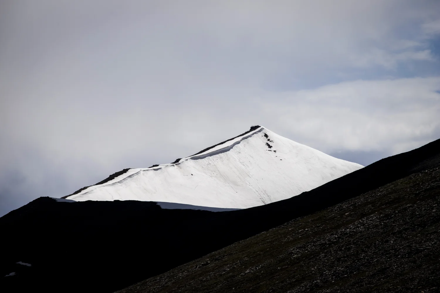 Verschneite Gipfel Berge unter Gewitter Himmel